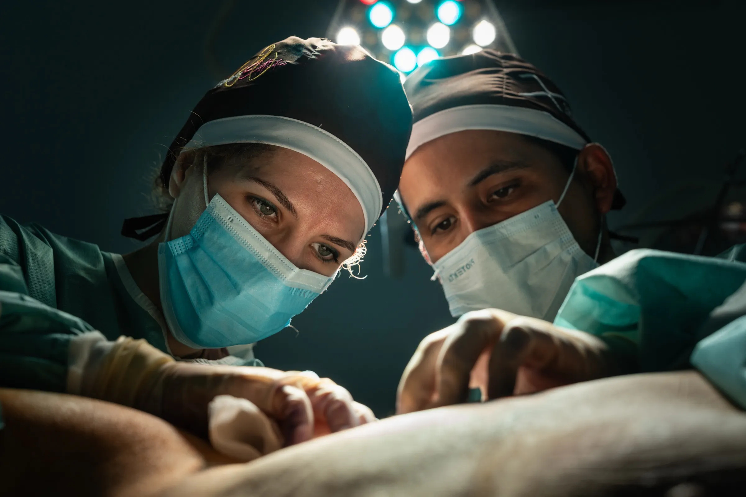 Two surgeons operating side by side under the lamps
