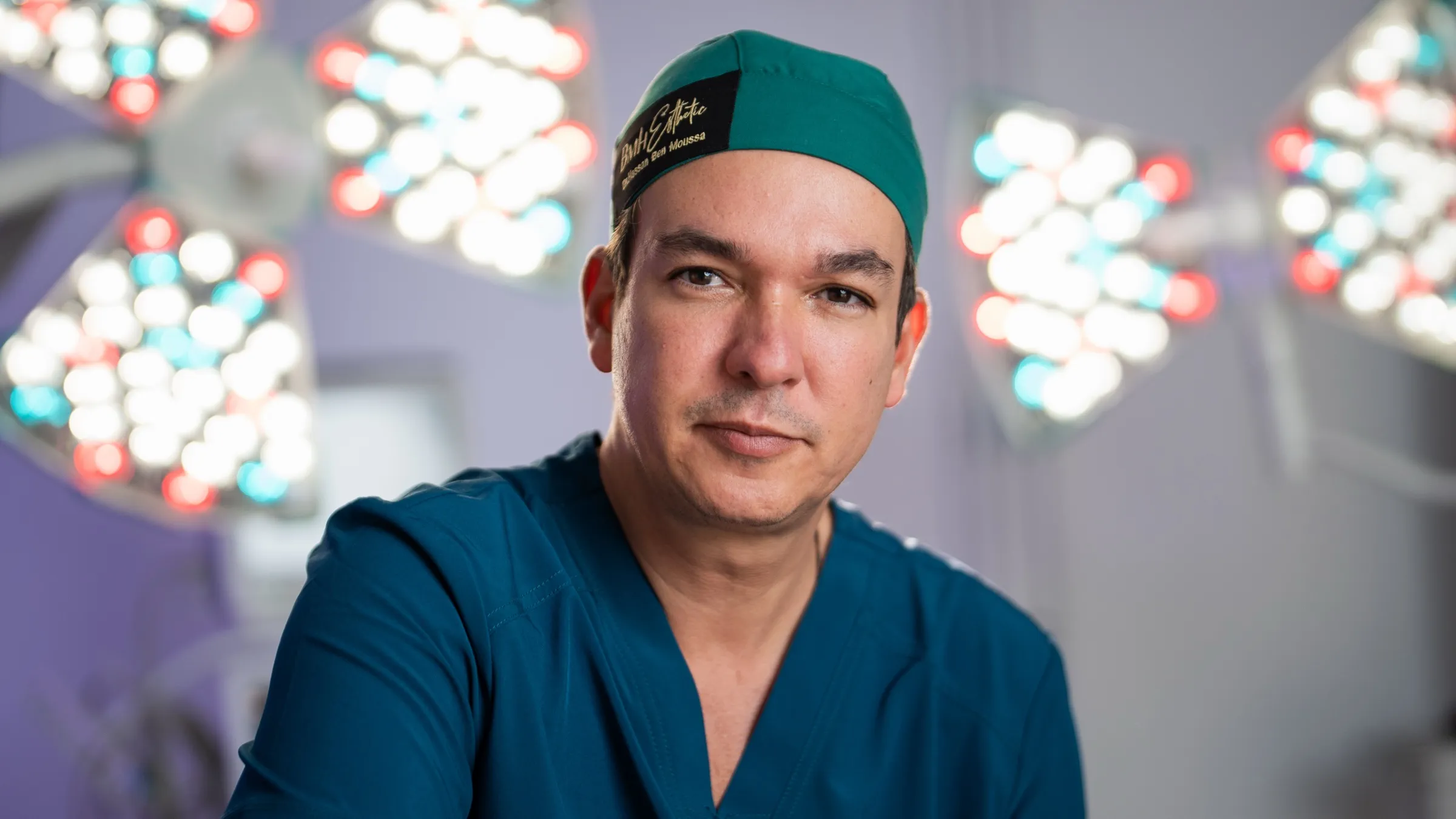 Surgeon in teal scrubs under the operating lamps
