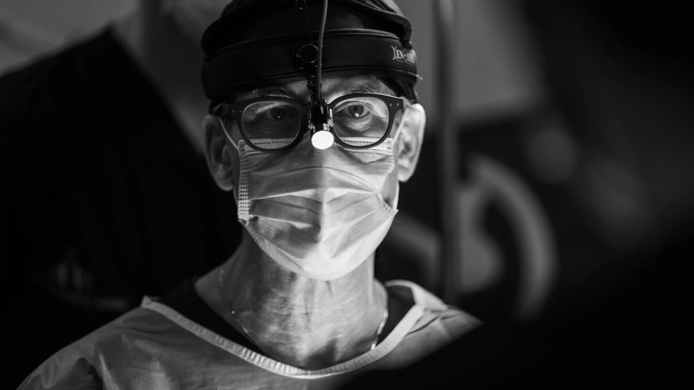 Black and white portrait of a surgeon with a headlamp